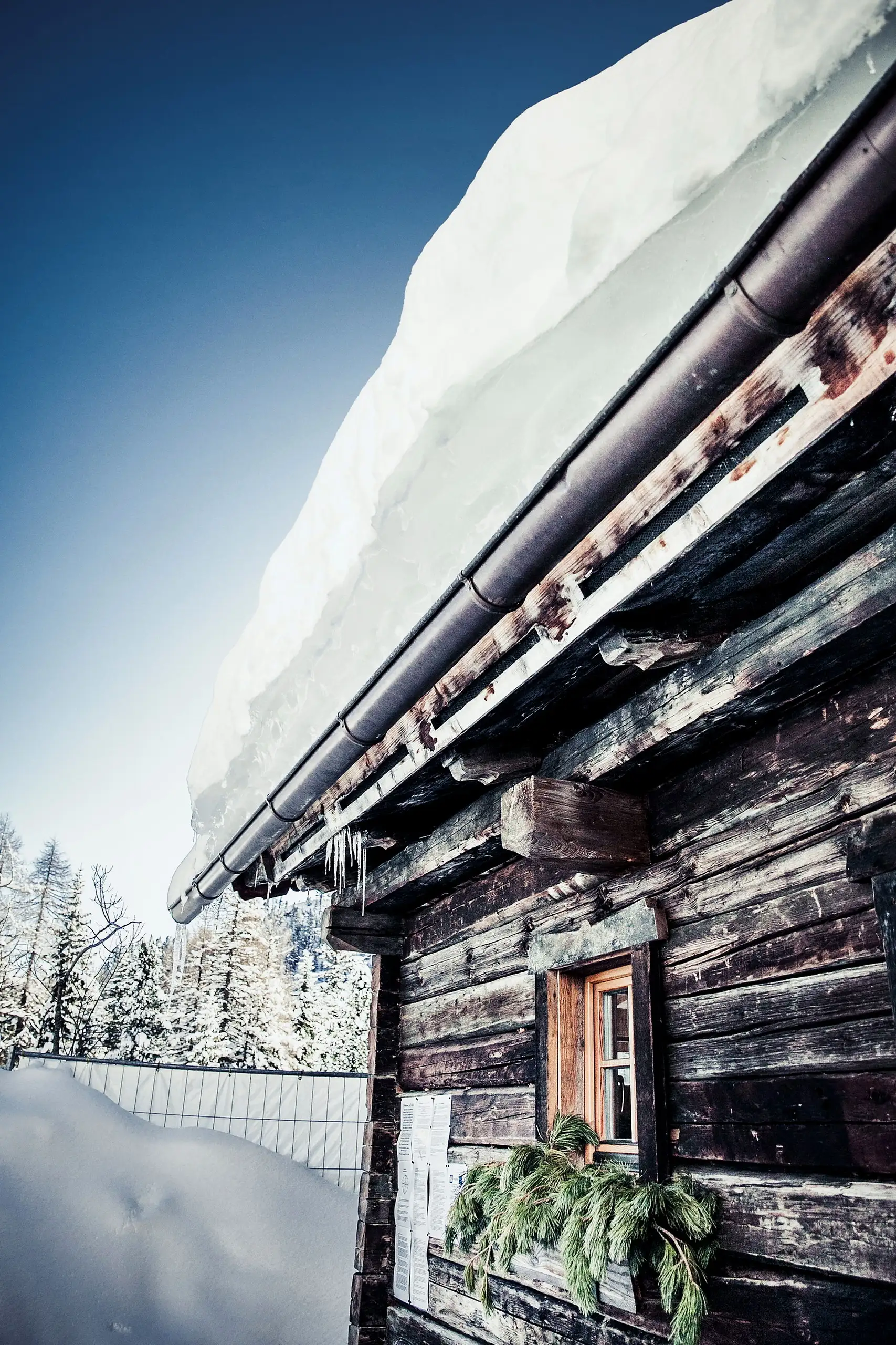Un’antica facciata in legno sotto un tetto coperto di neve sulla Turracher Höhe