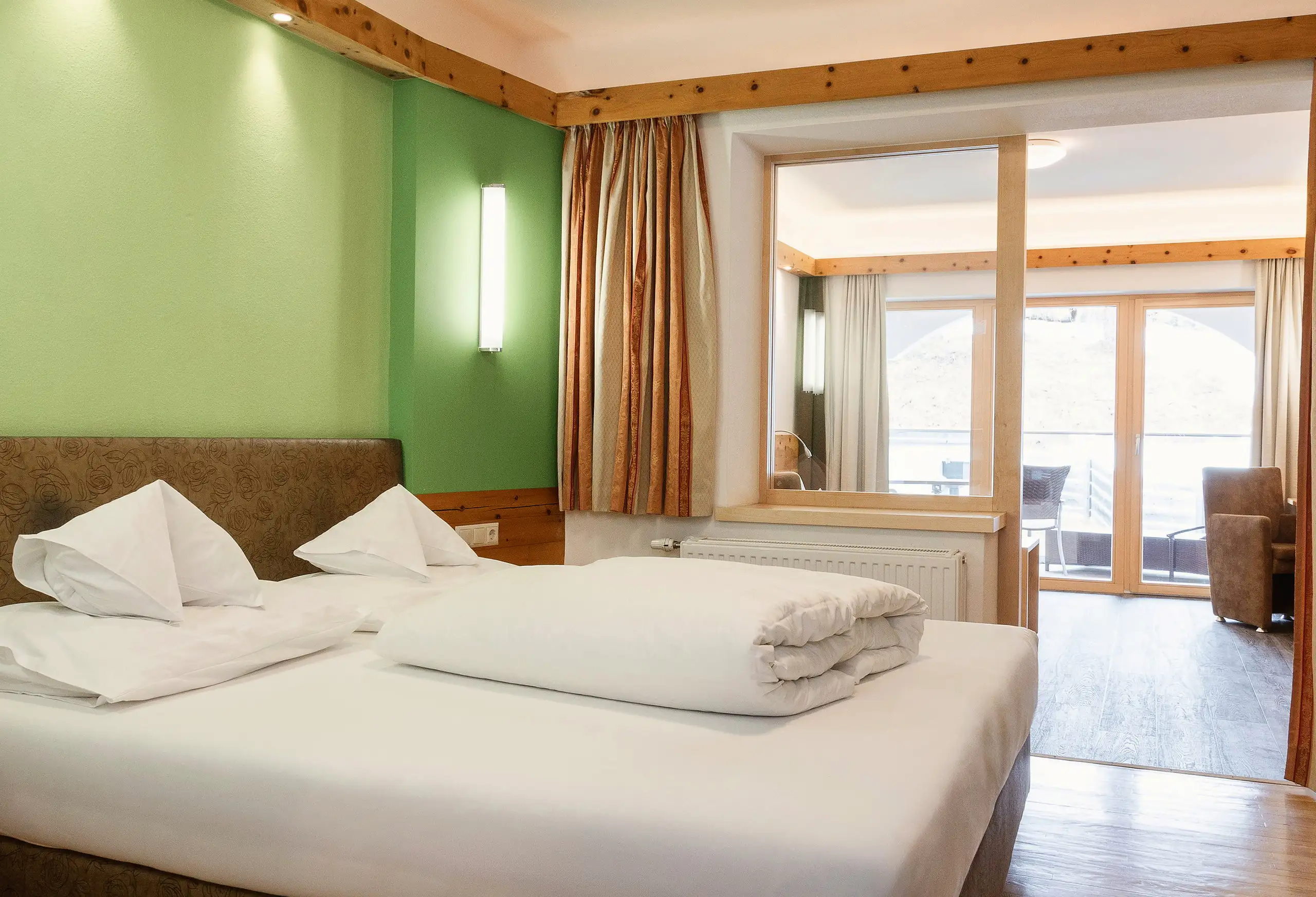 Junior suite König Ludwig s dřevěným stropem a dveřmi na balkon ve Schlosshotelu Seewirt